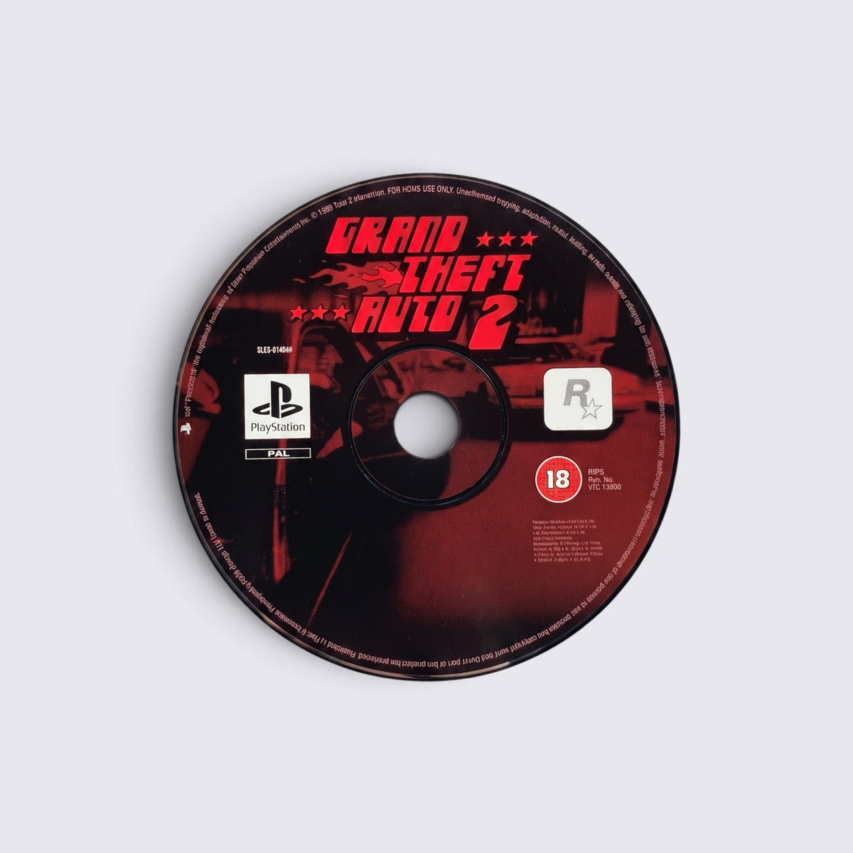 MrPixel Grand Theft Auto 2 PlayStation game disc with red logo and black background on a light grey surface