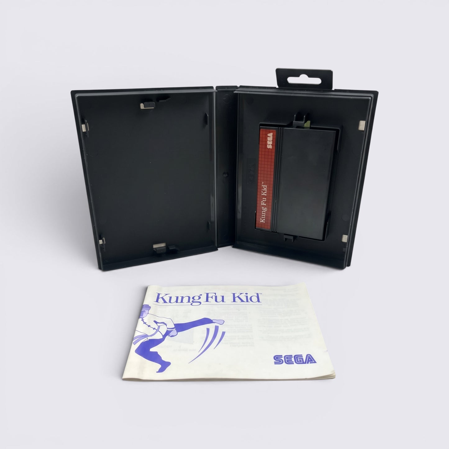 MrPixel Kung Fu Kid SEGA game cartridge in a black case with the original instruction manual on a grey surface.