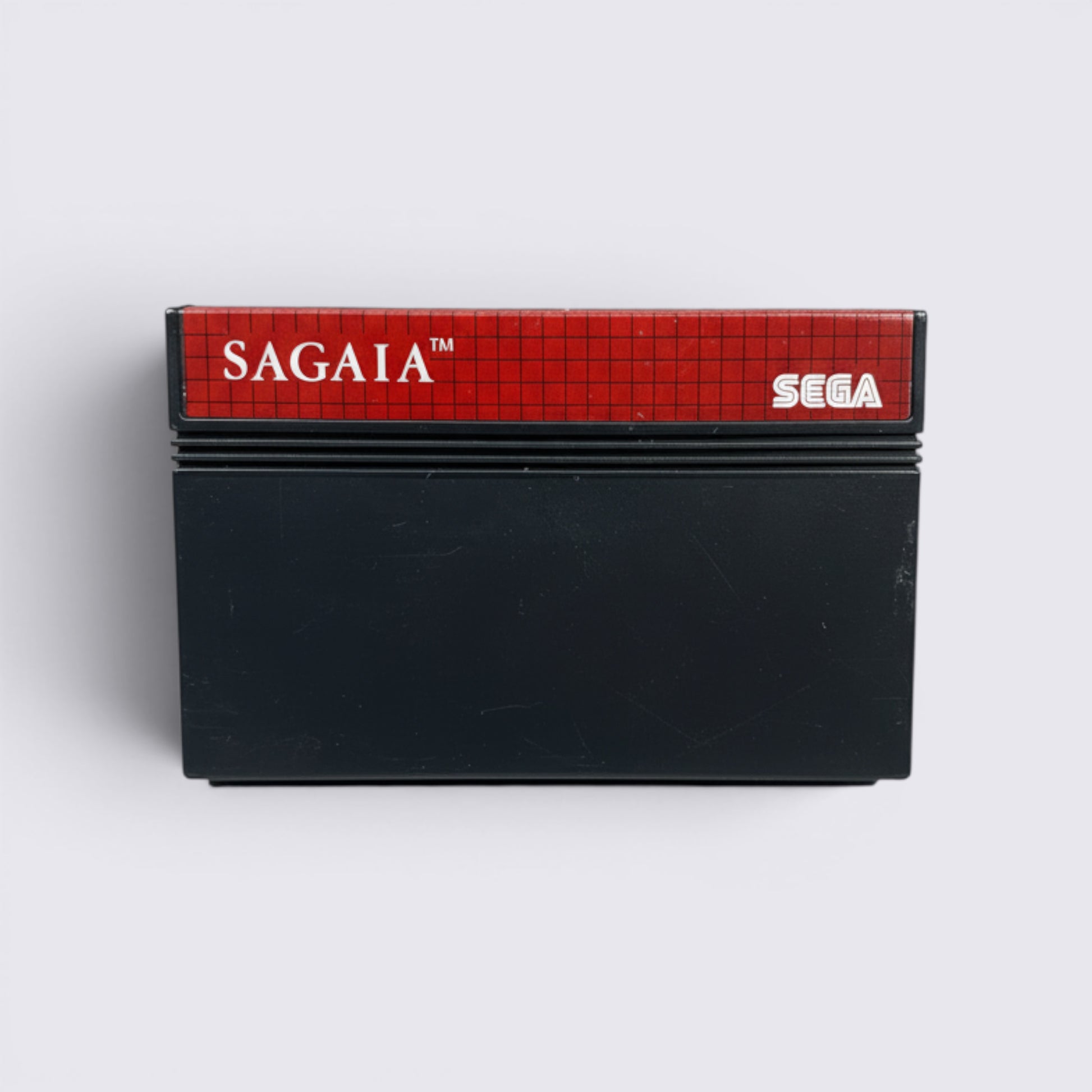 MrPixel Sagaia Sega Master System game cartridge with red grid label and black casing on a grey stone background