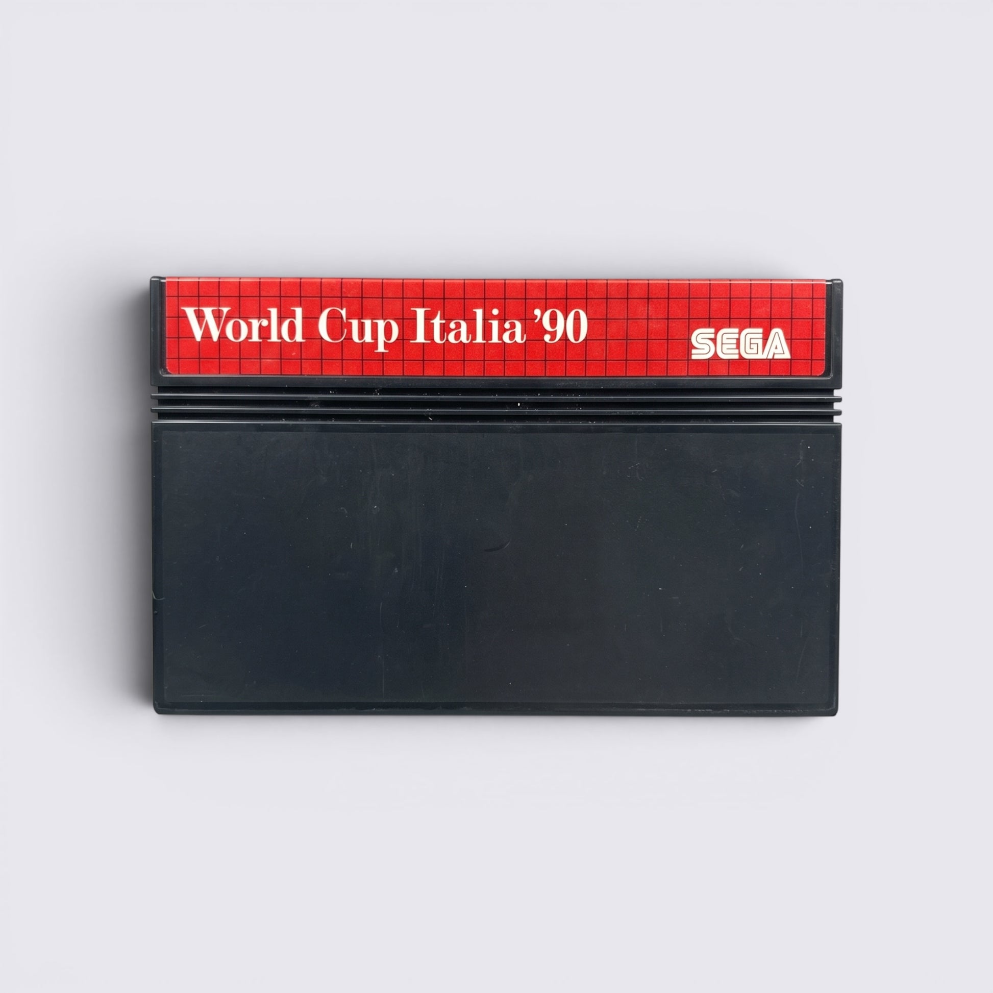 MrPixel World Cup Italia 90 Sega Master System game cartridge with red and black label on a grey stone background